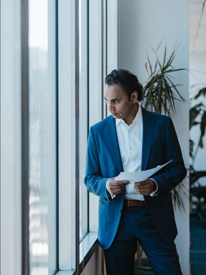 Investigator in a navy suit reviewing a file by a window